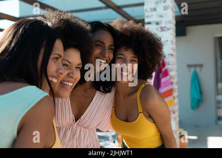 Jeunes amies biraciales gaies se couchant et posant tout en appréciant les vacances d'été ensemble Banque D'Images