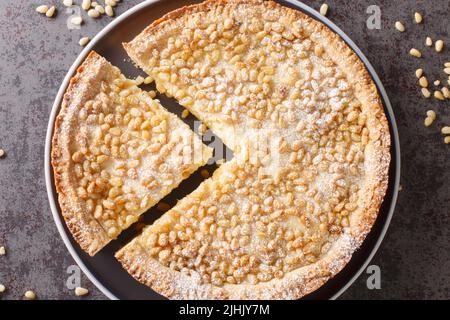 Tarte de grand-mère italienne avec crème anglaise et pignons dans une assiette sur la table. Vue horizontale du dessus Banque D'Images