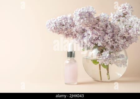 Huile naturelle ou sérum pour soins du visage ou des cheveux sur fond rose avec lilas dans le vase à proximité Banque D'Images