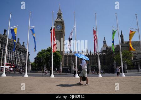 Un homme utilise un parapluie pour se protéger du soleil pendant qu'il passe devant les chambres du Parlement, Westminster. Les températures ont atteint 40C pour la première fois au Royaume-Uni, avec 40,2C provisoirement enregistrées à Londres Heathrow, a déclaré le bureau met. Date de la photo: Mardi 19 juillet 2022. Banque D'Images