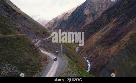 Vue aérienne par drone d'une voiture tout-terrain noire sur un chemin de terre dangereux entre dans les collines de montagne. VUS. Photo de haute qualité Banque D'Images