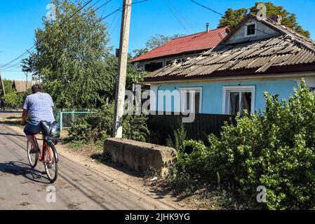 DACHNE, UKRAINE - 19 JUILLET 2022 - Un homme passe à vélo devant une maison endommagée à la suite d'une attaque de missiles russes, village de Dachne, région d'Odesa, SO Banque D'Images