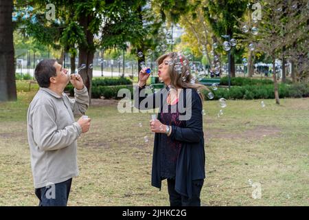 Couple de reines mûres et gaies qui soufflent des bulles dans un parc Banque D'Images