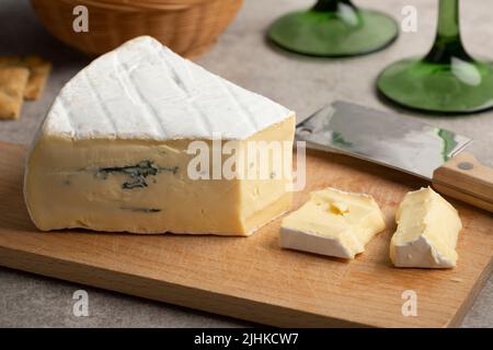 Morceau de Cambozola allemand doux, fromage brie bleu sur une planche à découper de près Banque D'Images