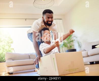 Conduire sa voiture imaginaire, propulsée par un père, pousser son fils dans une boîte tout en jouant ensemble à la maison. Banque D'Images