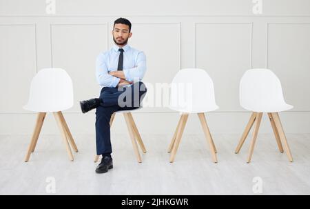 Pleine longueur d'homme d'affaires asiatique attendant une entrevue. Un jeune requérant impatient assis seul. Professionnel ethnique avec les bras pliés en ligne Banque D'Images