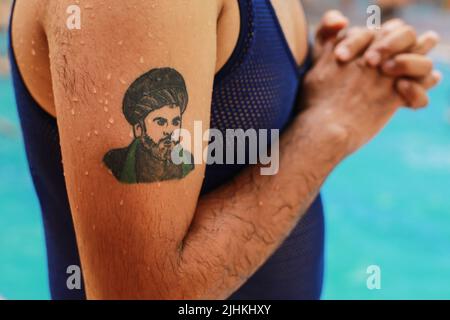 Bagdad, Irak. 19th juillet 2022. Un irakien est vu avec un portrait du religieux chiite irakien Muqtada al-Sadr tatoué sur son bras, dans un parc aquatique de Bagdad. L'Irak connaît une vague de chaleur avec des températures qui atteignent plus de 45 degrés Celsius. Credit: Ameer Al-Mohammadawi/dpa/Alamy Live News Banque D'Images