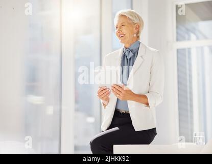 Une femme d'affaires caucasienne mûre et confiante et réfléchie qui envisage d'avoir une tablette numérique dans un bureau. Entrepreneur réussi et leader dévoué Banque D'Images
