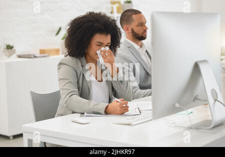 Jeune femme d'affaires de race mixte soufflant son nez avec un mouchoir en papier tout en s'asseyant à un bureau au travail. Femme d'affaires hispanique malade avec un afro mauriquement Banque D'Images
