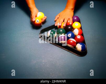 Mains préparant des boules de billard dans un rack triangulaire sur la table de billard Banque D'Images