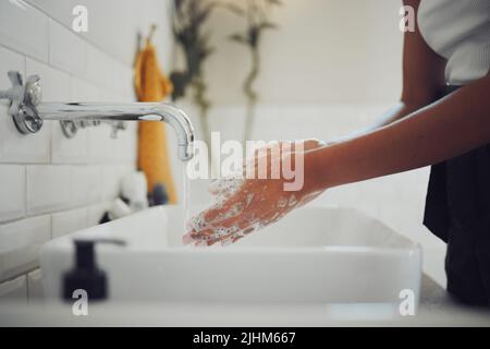 Gros plan des mains des femmes en utilisant du savon et en se lavant les mains avec de l'eau propre sous le robinet. La femme laiteuse et rince pour empêcher la propagation des germes Banque D'Images