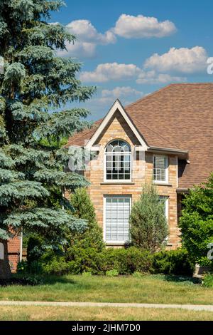 Fragment d'une maison avec un grenier et de l'épinette bleue sous des nuages blancs Banque D'Images