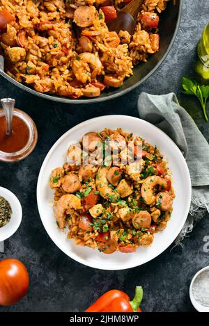 Jambalaya créole avec riz, saucisses fumées, viande de poulet et légumes sur fond de pierre sombre. Vue de dessus, plan d'installation, gros plan Banque D'Images