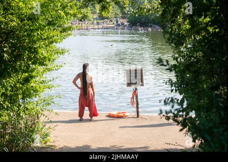 Londres, Royaume-Uni. 19th juillet 2022. Un homme se tient sur la rive du lac artificiel le Serpentine à Hyde Park, à côté d'un panneau indiquant « pas de baignade ». Dans la région de Londres, la température pourrait monter jusqu'à 40 degrés. Credit: Sebastian Gollnow/dpa/Alay Live News Banque D'Images