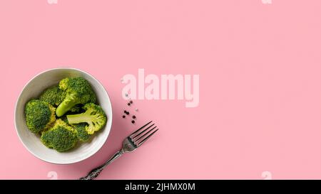 Fleurons de brocoli vert cru dans un bol et fourchette sur fond rose doux. Concept de détox antioxydant faible calorie dieting. Plats végétariens. Banque D'Images