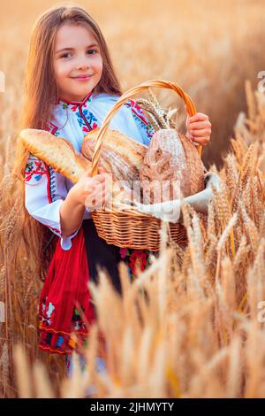 Une femme bulgare ou une jeune fille en robe traditionnelle folklorique tient dans les mains du blé doré et du pain maison fraîchement cuit dans un sac Banque D'Images