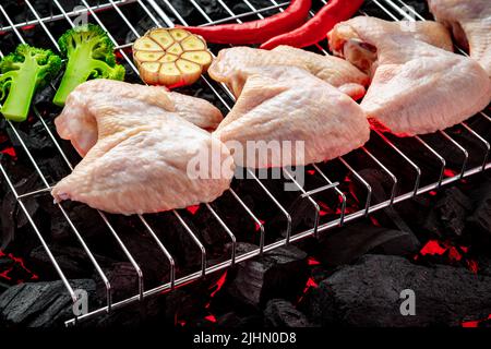 Ailes de poulet crues sur le gril, plats chauds du gril. Barbecue et grillades. Image très haute résolution Banque D'Images