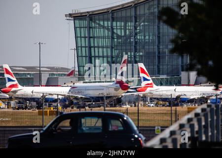 Londres, Royaume-Uni. 19th juillet 2022. Un taxi passe devant un avion de British Airways en préparation pour le décollage devant le terminal 5 de l'aéroport d'Heathrow le jour où la température la plus chaude jamais enregistrée au Royaume-Uni, 40,2C, y a été enregistrée. Le met Office a annoncé que Londres Heathrow a signalé une température de 40,2C à 12:50, ce qui fait provisoirement la première fois que le seuil de 40 degrés Celsius avait été brisé au Royaume-Uni. Crédit : Mark Kerrison/Alamy Live News Banque D'Images