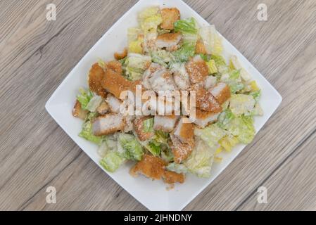 Vue en hauteur d'une assiette alléchante de salade césar au poulet croustillant, empilée en hauteur, vous permettra de vous assurer que le ventre sera plein. Banque D'Images