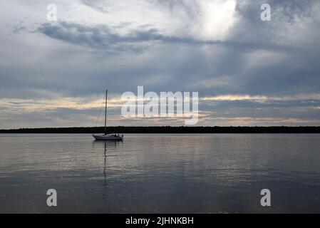 Un voilier ancré dans le lac supérieur au large de South Twin Island pendant le coucher du soleil sur le bord de mer national des îles Apôtres. Banque D'Images