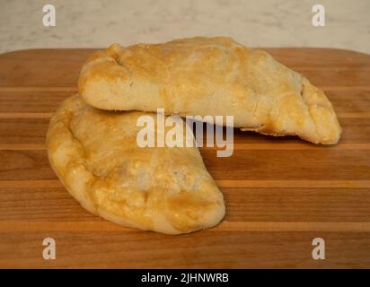 Deux patates de bœuf et de pommes de terre fraîchement cuites sur une planche à découper en bois. Banque D'Images