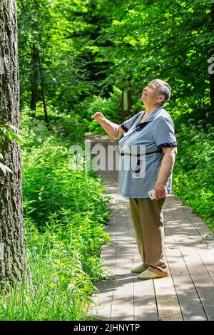 femme âgée marchant le long de la forêt, repos actif de pensionné, promenade de bien-être dans la nature.pensionnée femme ayant des activités de loisirs amusantes et intéressantes Banque D'Images