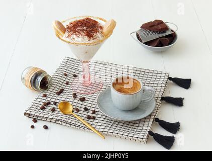 Tiramisu maison facile avec chocolat et café, dessert de style cheesecake sucré sans cuisson avec des ingrédients placés sur fond de table en bois blanc. Banque D'Images