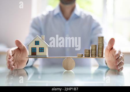 Petite maison modèle et des pièces d'or empilés en équilibre sur la balançoire en bois Banque D'Images