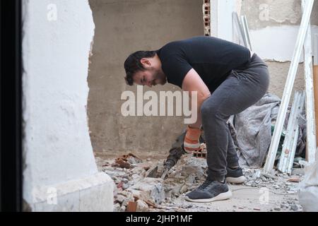 Un handyman utilisant un marteau pour percer dans le mur. Banque D'Images