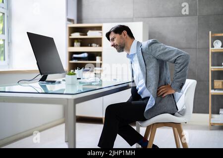 Mauvaise posture assise au bureau avec mal de dos dans la chaise Banque D'Images