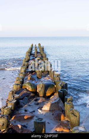 une vague de mer bat contre un brise-lames sur une plage de sable, longue exposition. Banque D'Images