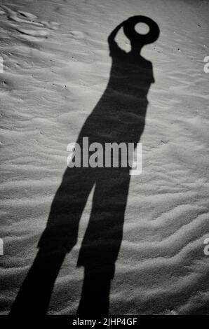 Une ombre dans le sable d'un homme avec un cercle au lieu d'une tête Banque D'Images