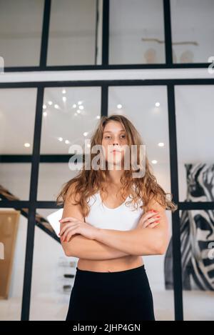 Une femme présente une combinaison de piste regarde l'appareil photo à l'intérieur. Banque D'Images