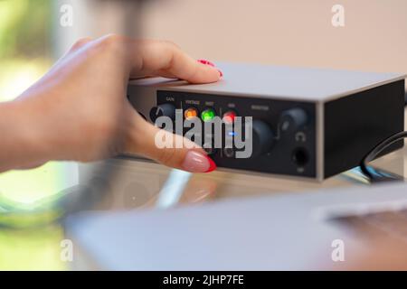 Jeunes femmes méconnaissables, mains, réglage du son du mélangeur audio en gros plan dans un studio à domicile Banque D'Images