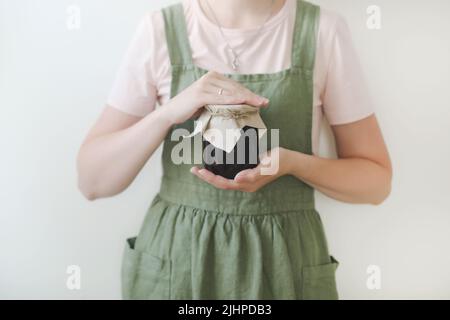 Femme femme femme au foyer dans un tablier tenant un pot en verre de confiture maison douce, gros plan Banque D'Images