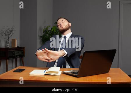 Un homme d'affaires fatigué et travailleur, assis au bureau tard dans la nuit. Concept de surcharge. Banque D'Images