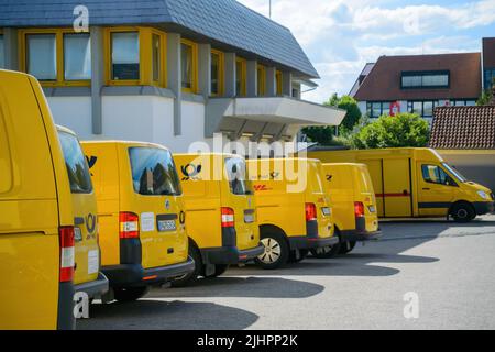 Oberkirch, Allemagne - 27 mai 2022: Vue latérale de la rangée de multiples fourgonnettes électriques jaunes Volkswagen avec le logotype Deutsche post DHL - garée près du centre de distribution postal Banque D'Images