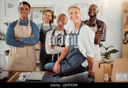 Groupe de cinq stylistes de vêtements divers et gais debout avec leurs bras croisés dans un magasin au travail. Rires et sourires souriants Banque D'Images