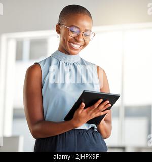 Jeune femme d'affaires afro-américaine joyeuse travaillant sur une seule tablette numérique au travail. Bonne femme noire souriant en utilisant les médias sociaux sur un Banque D'Images