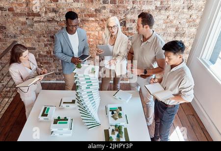 Groupe d'architectes divers discutant des plans, des plans et des schémas lors d'une réunion dans leur salle de conférence. Les gens d'affaires brainstorming et Banque D'Images