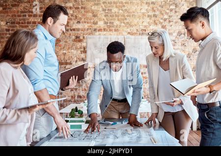 Groupe d'architectes divers discutant des plans, des plans et des schémas lors d'une réunion dans leur salle de conférence. Les gens d'affaires brainstorming et Banque D'Images