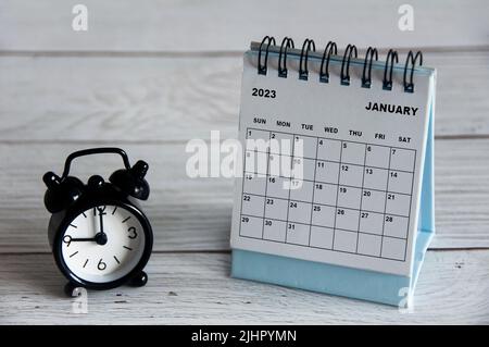 Calendrier de bureau blanc de janvier 2023 avec réveil noir pointant à 9 heures sur une table en bois. Concept de calendrier Banque D'Images