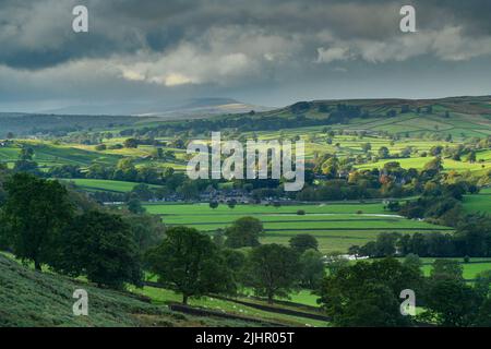 Paysage de Burnsall dans la vallée (pentes à flanc de colline, hautes terres, champs verts et pâturages, murs en pierre sèche, ciel nuageux et soleil) - Upper Wharfedale, Angleterre, Royaume-Uni. Banque D'Images