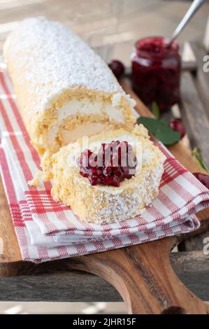 Dessert à la cerise avec un rouleau suisse rempli de crème fouettée et recouvert de compote Banque D'Images