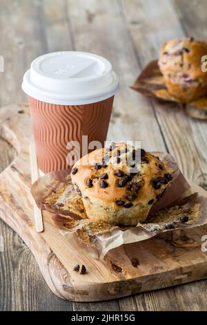 Un muffin aux pépites de chocolat servi avec du café dans une tasse de papier recyclable. Banque D'Images