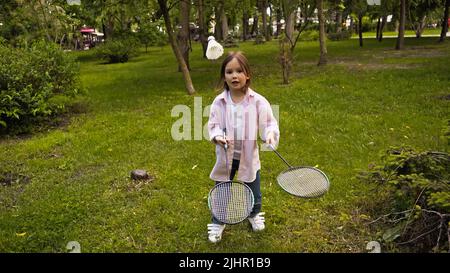 enfant vêtu d'un vêtement décontracté jouant au badminton sur l'herbe verte dans le parc Banque D'Images