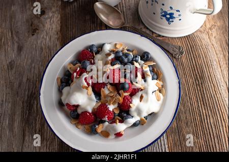 Petit déjeuner à base de carb avec baies, yaourt et amandes grillées sur une table rustique et en bois Banque D'Images
