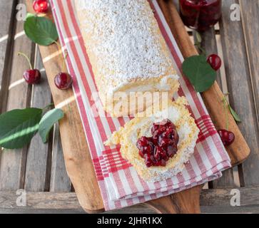 Dessert à la cerise avec un rouleau suisse rempli de crème fouettée et recouvert de compote Banque D'Images