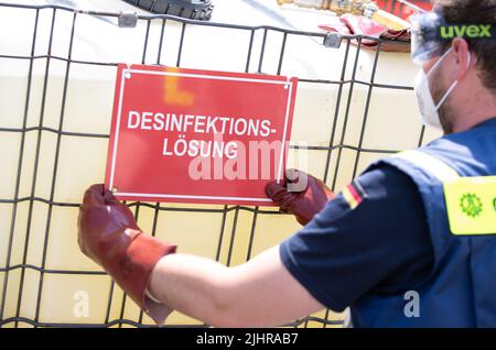 Nordhorn, Allemagne. 20th juillet 2022. Un employé de l'Agence fédérale allemande de secours technique (THW) se trouve dans un réservoir de solution désinfectante. Les véhicules sont nettoyés dans une installation de décontamination s'ils se trouvent dans une ferme située dans une zone de surveillance. À la suite de l'épidémie de peste porcine africaine dans une ferme du sud de l'Emsland, les comtés touchés prennent des mesures supplémentaires pour lutter contre la maladie animale. Un centre conjoint de logistique sur les maladies animales a commencé ses opérations dans les comtés de Grafschaft Bentheim et d'Emsland, à Nordhorn. Credit: Friso Gentsch/dpa/Alay Live News Banque D'Images