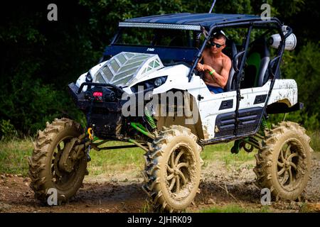 Un VTT avec des gens qui se conduisent et qui s'y conduisent sur un terrain sale et boueux au Rock Fest en 2020 Banque D'Images